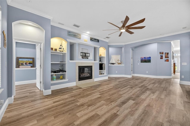 5720 Tortoise Pl, Apollo Beach, FL 33572 - unfurnished living room featuring ceiling fan, crown molding, wood finished floors, a fireplace, and arched walkways