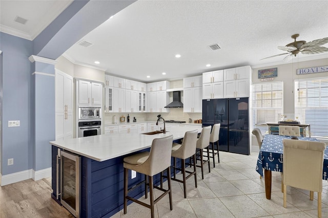 5720 Tortoise Pl, Apollo Beach, FL 33572 - kitchen with stainless steel appliances, beverage cooler, wall chimney exhaust hood, ornamental molding, and ceiling fan