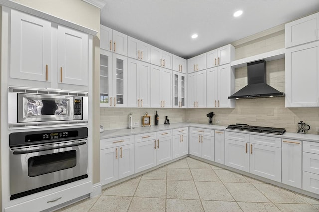 5720 Tortoise Pl, Apollo Beach, FL 33572 - kitchen with stainless steel appliances, wall chimney range hood, decorative backsplash, light countertops, and recessed lighting
