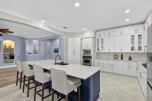 5720 Tortoise Pl, Apollo Beach, FL 33572 - kitchen featuring appliances with stainless steel finishes, arched walkways, recessed lighting, light stone counters, and white cabinets