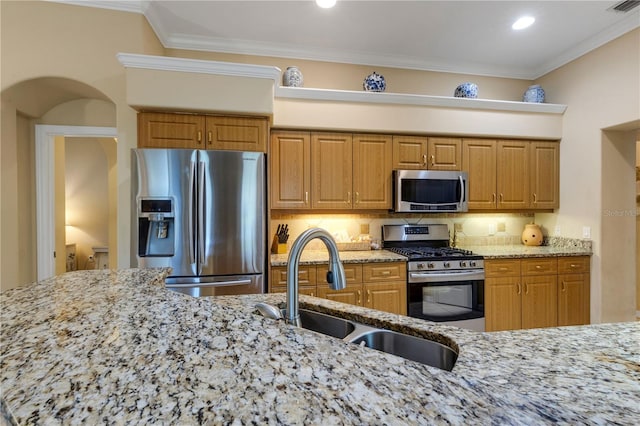 3503 92nd Ave E, Parrish, FL 34219 - kitchen featuring stainless steel appliances, light stone counters, tasteful backsplash, crown molding, and brown cabinets