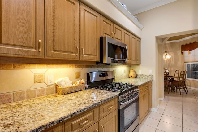 3503 92nd Ave E, Parrish, FL 34219 - kitchen with appliances with stainless steel finishes, light stone counters, decorative backsplash, light tile patterned floors, and ornamental molding