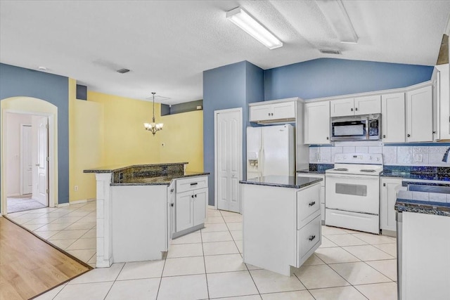 1462 Lake Shore Ranch Dr, Seffner, FL 33584 - kitchen featuring white appliances, a kitchen island, tasteful backsplash, arched walkways, and vaulted ceiling