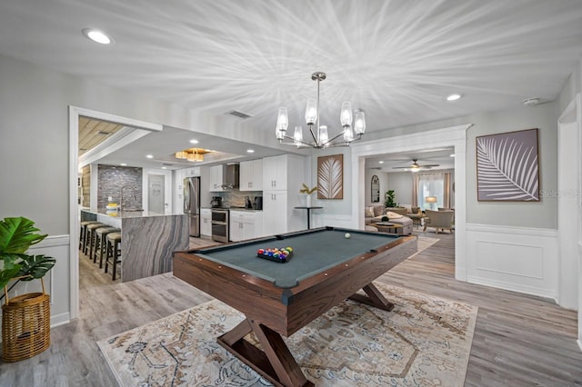 4545 Harbor Hills Dr, Largo, FL 33770 - rec room with billiards table, a chandelier, light wood-type flooring, a wainscoted wall, and a ceiling fan