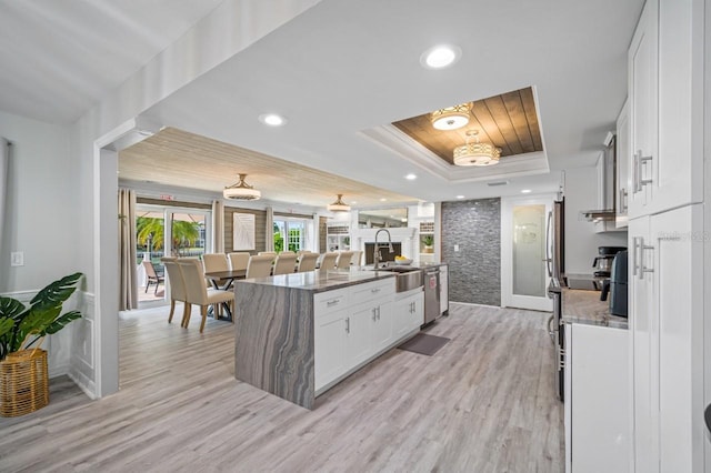 4545 Harbor Hills Dr, Largo, FL 33770 - kitchen with a raised ceiling, white cabinets, wood ceiling, light wood-type flooring, and a kitchen island with sink