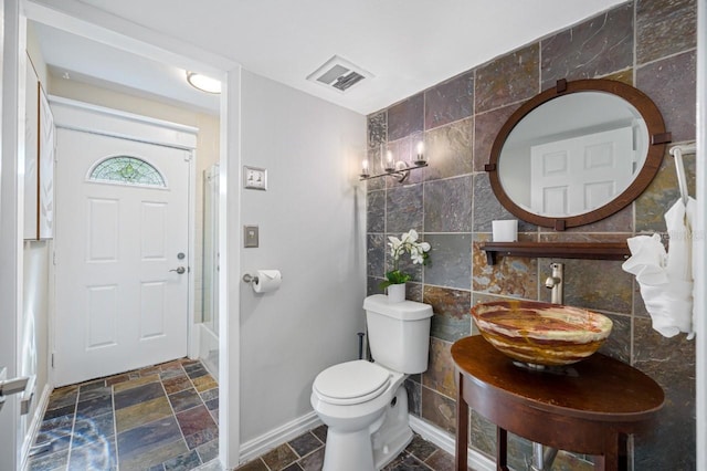 4545 Harbor Hills Dr, Largo, FL 33770 - bathroom featuring tile walls, stone tile floors, and tub / shower combination