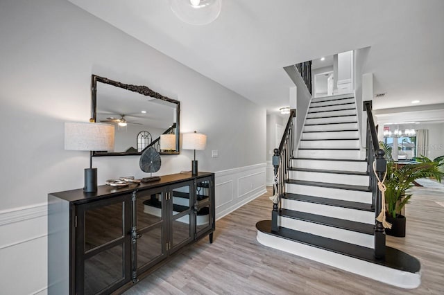 4545 Harbor Hills Dr, Largo, FL 33770 - stairway with wood finished floors, a wainscoted wall, ceiling fan, a decorative wall, and a chandelier