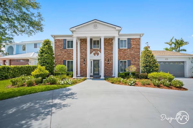 4545 Harbor Hills Dr, Largo, FL 33770 - greek revival house with brick siding, concrete driveway, and a garage