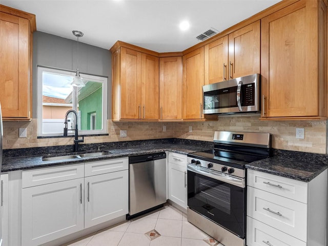 540 80th Ave, St Pete Beach, FL 33706 - kitchen with appliances with stainless steel finishes, backsplash, light tile patterned floors, dark stone countertops, and hanging light fixtures