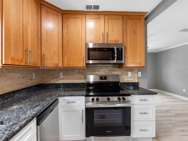 540 80th Ave, St Pete Beach, FL 33706 - kitchen featuring appliances with stainless steel finishes, dark stone counters, tasteful backsplash, and light wood finished floors