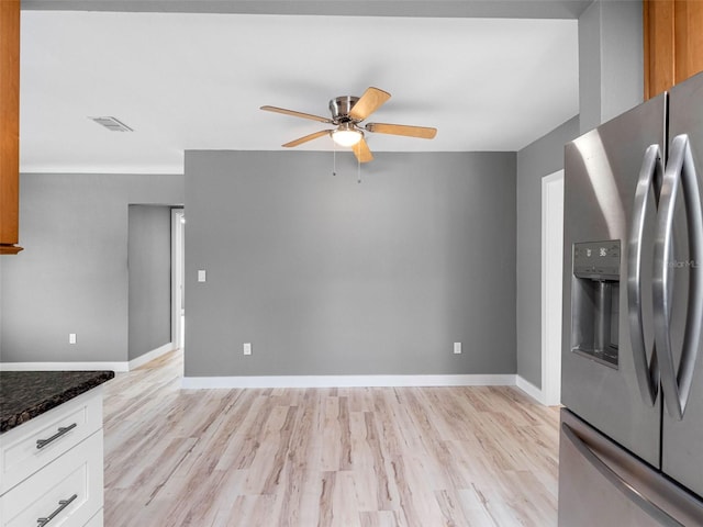540 80th Ave, St Pete Beach, FL 33706 - kitchen featuring stainless steel fridge, a ceiling fan, dark stone counters, light wood-style floors, and white cabinetry