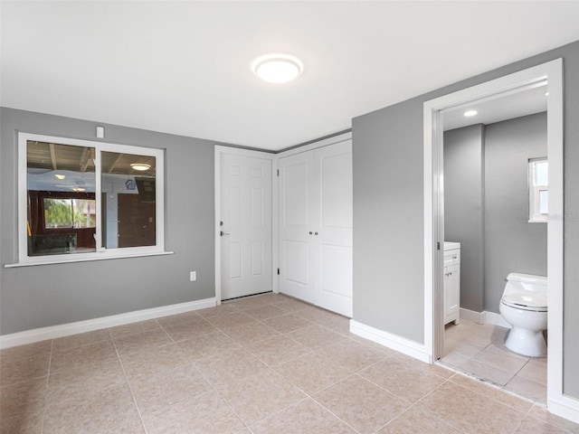 540 80th Ave, St Pete Beach, FL 33706 - unfurnished bedroom featuring light tile patterned floors, ensuite bath, multiple windows, and a closet