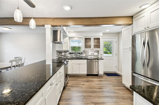 12835 74th Ave, Seminole, FL 33776 - kitchen with appliances with stainless steel finishes, wall chimney range hood, white cabinetry, light wood finished floors, and tasteful backsplash