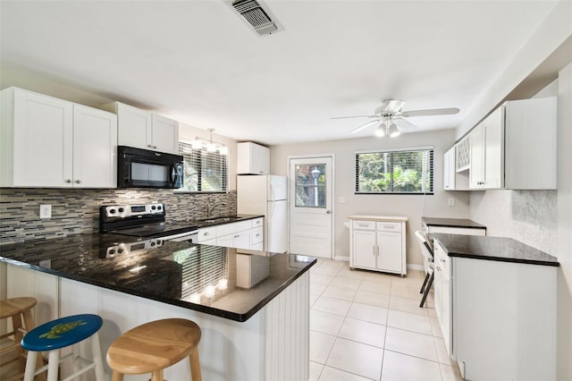 12835 74th Ave, Seminole, FL 33776 - kitchen featuring black microwave, freestanding refrigerator, stainless steel electric stove, a peninsula, and backsplash