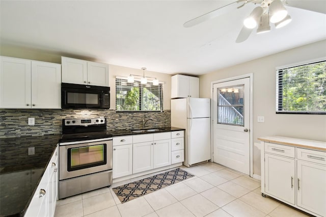 12835 74th Ave, Seminole, FL 33776 - kitchen featuring black microwave, electric stove, freestanding refrigerator, tasteful backsplash, and white cabinetry