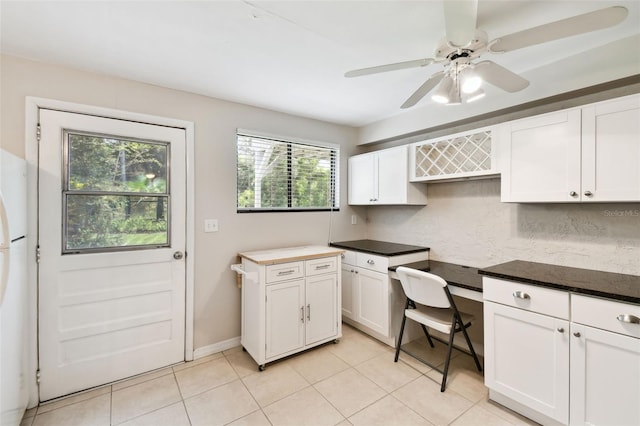 12835 74th Ave, Seminole, FL 33776 - kitchen with built in desk, light tile patterned floors, white cabinetry, freestanding refrigerator, and dark countertops