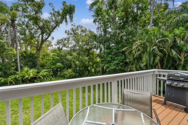 12835 74th Ave, Seminole, FL 33776 - wooden terrace featuring outdoor dining area, area for grilling, a lawn, and view of wooded area