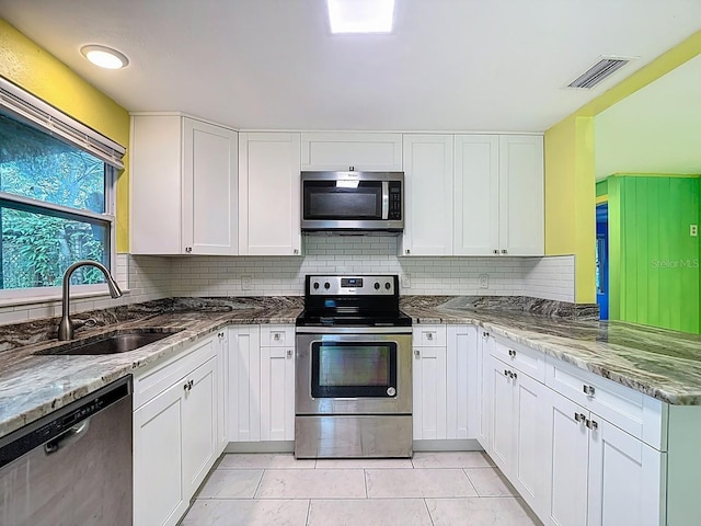 6428 Old Main St, New Port Richey, FL 34653 - kitchen with appliances with stainless steel finishes, white cabinetry, decorative backsplash, and stone countertops