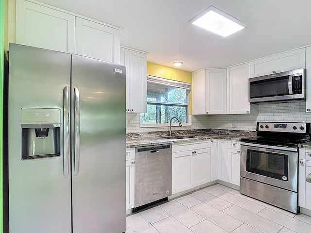 6428 Old Main St, New Port Richey, FL 34653 - kitchen featuring appliances with stainless steel finishes, decorative backsplash, white cabinetry, and dark stone counters