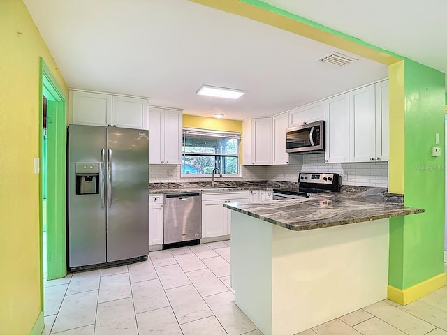 6428 Old Main St, New Port Richey, FL 34653 - kitchen with stainless steel appliances, a peninsula, backsplash, and white cabinetry