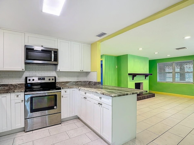 6428 Old Main St, New Port Richey, FL 34653 - kitchen featuring appliances with stainless steel finishes, a peninsula, tasteful backsplash, white cabinetry, and dark stone countertops