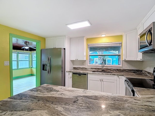 6428 Old Main St, New Port Richey, FL 34653 - kitchen featuring stainless steel appliances, dark stone counters, white cabinets, backsplash, and ceiling fan