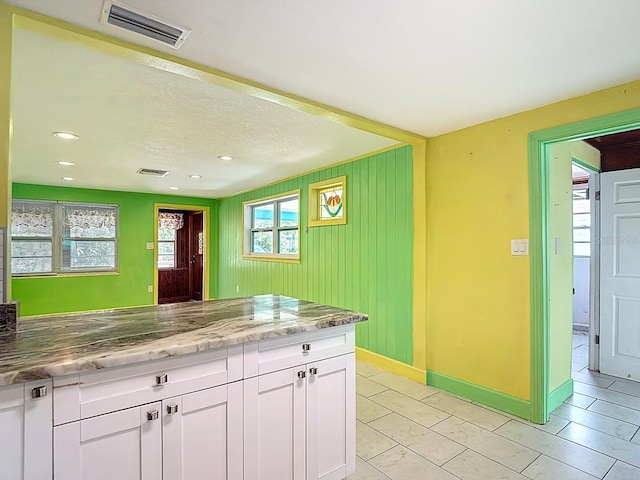 6428 Old Main St, New Port Richey, FL 34653 - kitchen with white cabinets, light stone countertops, light tile patterned floors, and recessed lighting