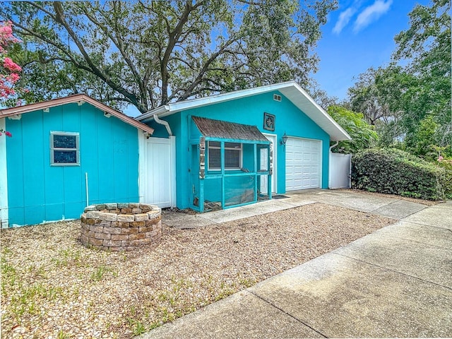 6428 Old Main St, New Port Richey, FL 34653 - view of front of home with an attached garage, driveway, board and batten siding, and an outdoor fire pit