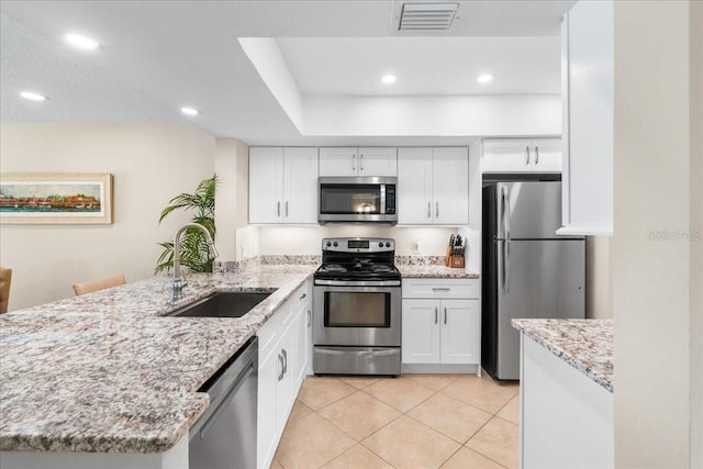 13000 Gulf Blvd Unit 309, Madeira Beach, FL 33708 - kitchen featuring a peninsula, appliances with stainless steel finishes, white cabinetry, light tile patterned floors, and recessed lighting