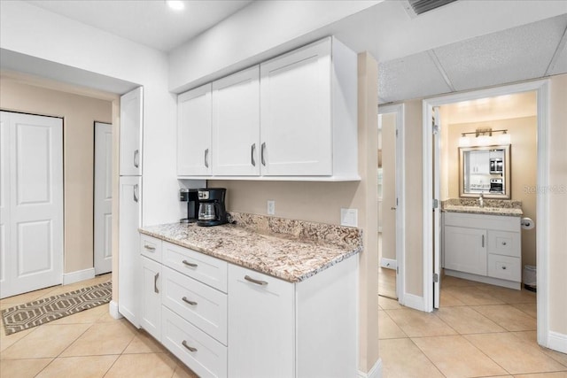 13000 Gulf Blvd Unit 309, Madeira Beach, FL 33708 - kitchen with light tile patterned flooring, white cabinetry, and light stone countertops