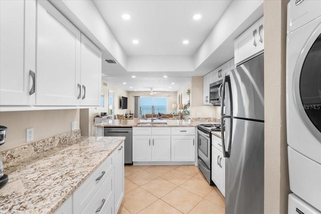 13000 Gulf Blvd Unit 309, Madeira Beach, FL 33708 - kitchen with washer / clothes dryer, appliances with stainless steel finishes, white cabinets, a peninsula, and light stone counters