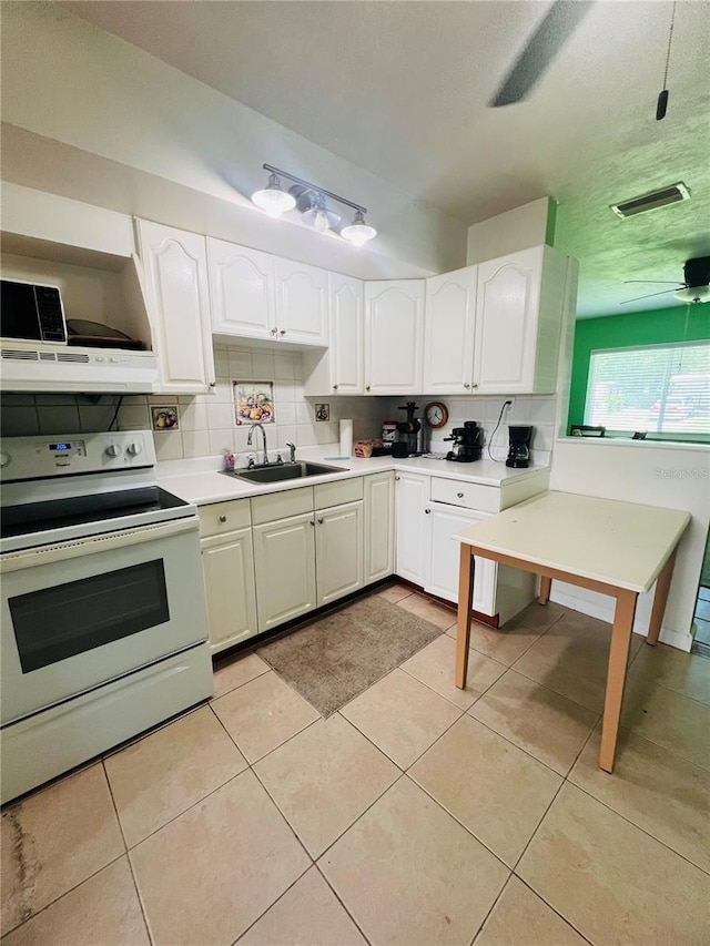 6316 Alaska Ave, New Port Richey, FL 34653 - kitchen with white electric range, decorative backsplash, white cabinets, light countertops, and under cabinet range hood