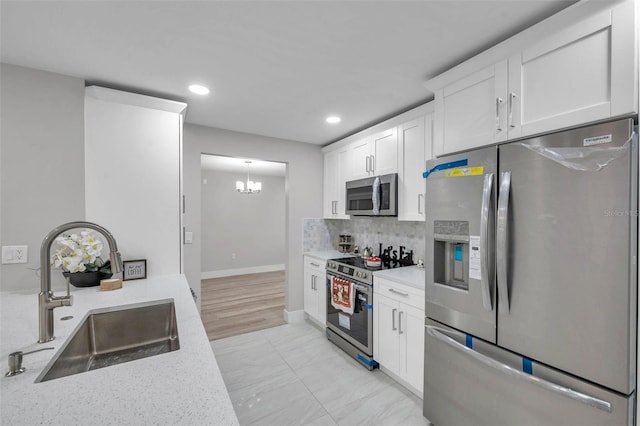2585 Ridge Ln, Palm Harbor, FL 34684 - kitchen with appliances with stainless steel finishes, a chandelier, white cabinets, tasteful backsplash, and recessed lighting
