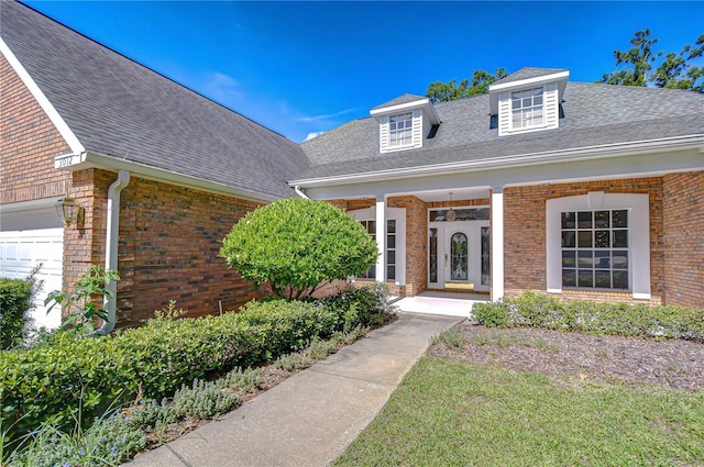 3012 Colonial Ridge Dr, Brandon, FL 33511 - entrance to property featuring brick siding, roof with shingles, covered porch, and an attached garage