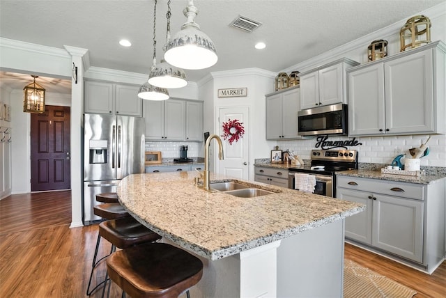 10603 Avian Forrest Dr, Riverview, FL 33578 - kitchen featuring appliances with stainless steel finishes, gray cabinetry, light stone countertops, a center island with sink, and a kitchen breakfast bar