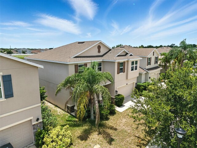 10603 Avian Forrest Dr, Riverview, FL 33578 - view of side of home featuring an attached garage, a shingled roof, a residential view, stucco siding, and stone siding