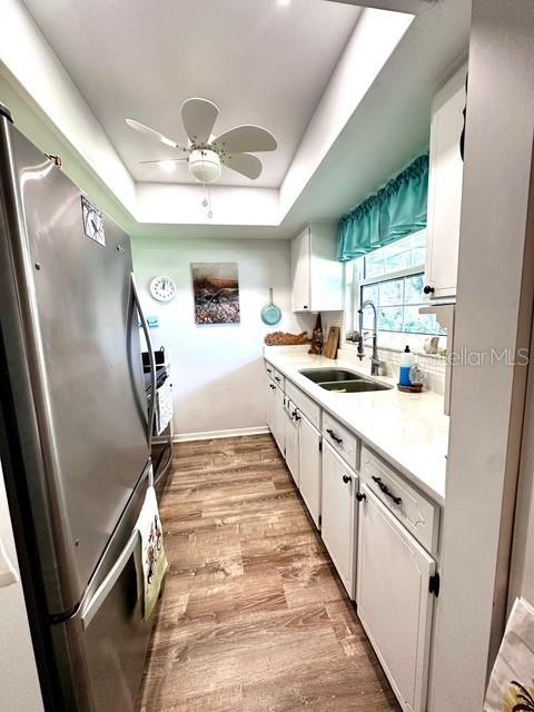 1701 Pinehurst Rd Unit 13C, Dunedin, FL 34698 - kitchen with freestanding refrigerator, a raised ceiling, white cabinets, and a ceiling fan