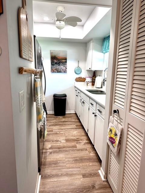 1701 Pinehurst Rd Unit 13C, Dunedin, FL 34698 - kitchen featuring light wood-type flooring, ceiling fan, white cabinetry, and light countertops