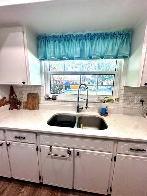 1701 Pinehurst Rd Unit 13C, Dunedin, FL 34698 - kitchen featuring white cabinets, light countertops, and backsplash