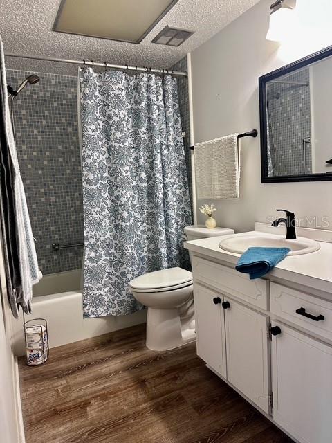 1701 Pinehurst Rd Unit 13C, Dunedin, FL 34698 - full bathroom with vanity, wood finished floors, shower / bath combo with shower curtain, and a textured ceiling
