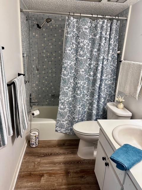 1701 Pinehurst Rd Unit 13C, Dunedin, FL 34698 - bathroom featuring vanity, shower / tub combo with curtain, wood finished floors, and a textured ceiling