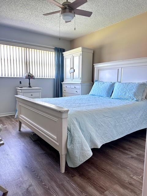 1701 Pinehurst Rd Unit 13C, Dunedin, FL 34698 - bedroom with wood finished floors, a textured ceiling, and a ceiling fan