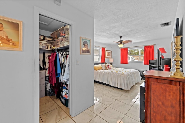 13565 86th Ave, Seminole, FL 33776 - bedroom with a walk in closet, a ceiling fan, a textured ceiling, and attic access