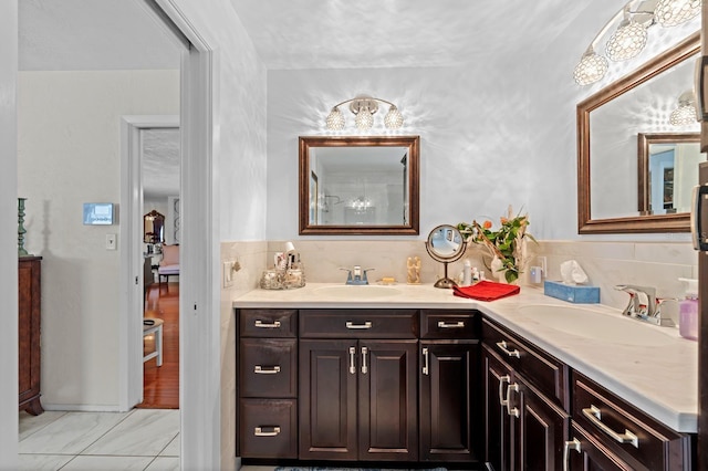 13565 86th Ave, Seminole, FL 33776 - bathroom featuring double vanity, marble look tiles, and decorative backsplash