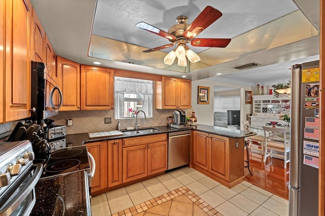 13565 86th Ave, Seminole, FL 33776 - kitchen featuring stainless steel appliances, light tile patterned floors, a ceiling fan, tasteful backsplash, and a peninsula