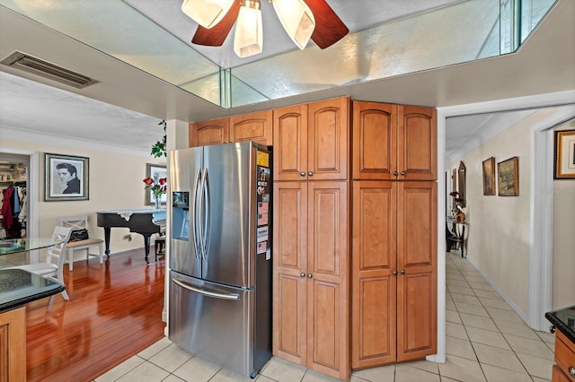13565 86th Ave, Seminole, FL 33776 - kitchen with stainless steel fridge, light tile patterned flooring, ceiling fan, and brown cabinetry