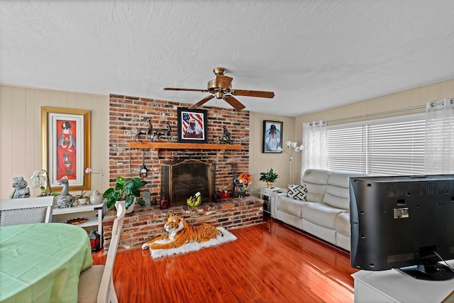 13565 86th Ave, Seminole, FL 33776 - living area featuring a ceiling fan, wood finished floors, a brick fireplace, and a textured ceiling