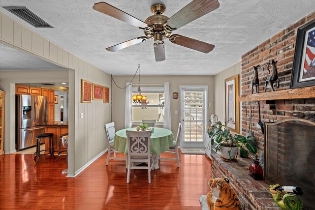 13565 86th Ave, Seminole, FL 33776 - dining area with light wood-style flooring, a textured ceiling, a ceiling fan, and a brick fireplace