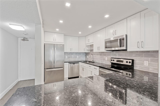51 Island Way Unit 411, Clearwater Beach, FL 33767 - kitchen with appliances with stainless steel finishes, dark stone counters, decorative backsplash, white cabinetry, and recessed lighting