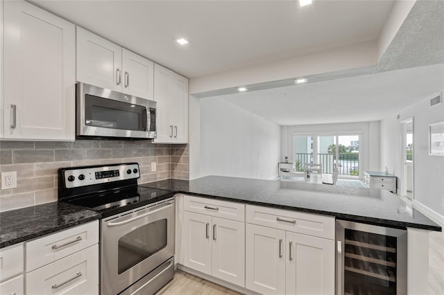 51 Island Way Unit 411, Clearwater Beach, FL 33767 - kitchen with stainless steel appliances, wine cooler, a peninsula, white cabinets, and dark stone counters